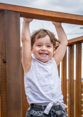 Obraz premium small toddler hanging upside down on a wooden ledge by itself