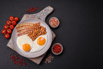 English breakfast with fried eggs, bacon, beans, tomatoes, spices and herbs