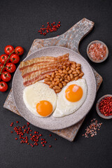 English breakfast with fried eggs, bacon, beans, tomatoes, spices and herbs