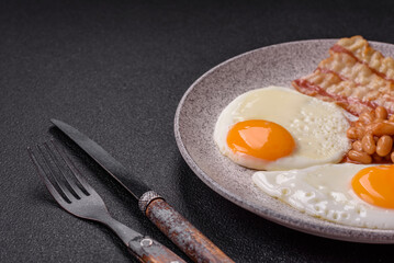 English breakfast with fried eggs, bacon, beans, tomatoes, spices and herbs