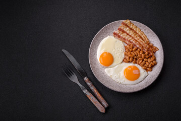 English breakfast with fried eggs, bacon, beans, tomatoes, spices and herbs