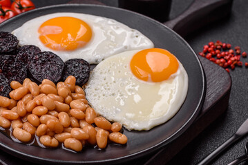 English breakfast with fried eggs, bacon, beans, tomatoes, spices and herbs