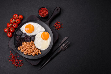 English breakfast with fried eggs, bacon, beans, tomatoes, spices and herbs