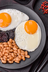 English breakfast with fried eggs, bacon, beans, tomatoes, spices and herbs