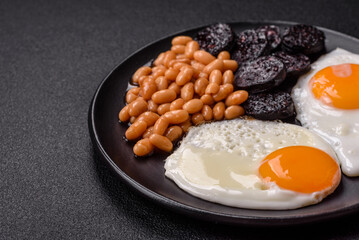 English breakfast with fried eggs, bacon, beans, tomatoes, spices and herbs