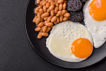 English breakfast with fried eggs, bacon, beans, tomatoes, spices and herbs