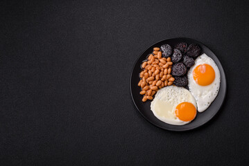 English breakfast with fried eggs, bacon, beans, tomatoes, spices and herbs