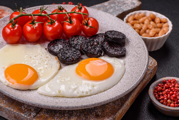 English breakfast with fried eggs, bacon, beans, tomatoes, spices and herbs
