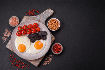 English breakfast with fried eggs, bacon, beans, tomatoes, spices and herbs
