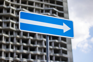 A blue sign displaying an arrow pointing towards the right
