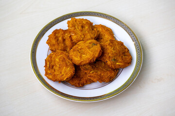 Homemade tasty Pakora on a white plate on a wooden background.
