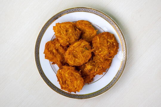 Homemade delicious Pakora on a white plate on a wooden background. Top view