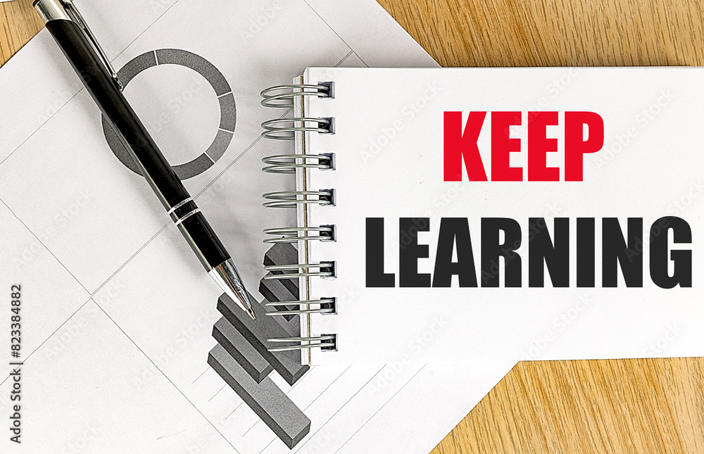 Aufkleber keep learning text on notebook with chart on wooden background