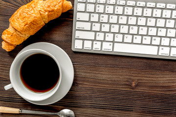 woman breakfast with coffee and croissant in office on wooden background top view mockup