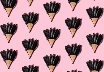 Creative pattern made of fan with black feathers on pink background. Minimal abstract idea.