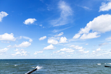 Baltic sea coastal view with breakwaters under cloudy blue sky
