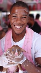 A man is holding a small dog and smiling. The dog is wearing a pink vest