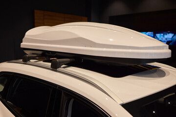White vehicle with roof box, hood, grille, bumper and automotive lighting