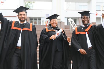 education, graduation and people concept - group of happy international students in mortar boards...