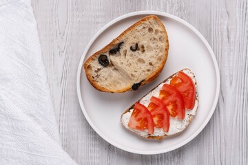 Slice of bread with cottage cheese and tomatoes on a white wooden background