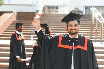 Handsome indian graduate in graduation glow with diploma