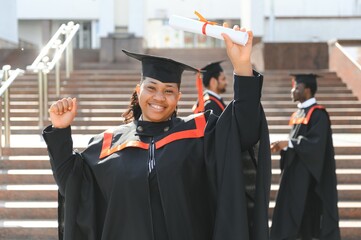 pretty african female college graduate at graduation with classmates