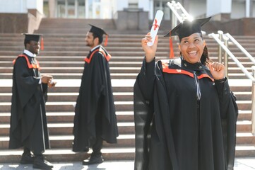 pretty african female college graduate at graduation with classmates