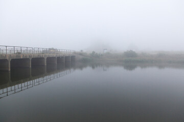View of the bridge on the foggy lake