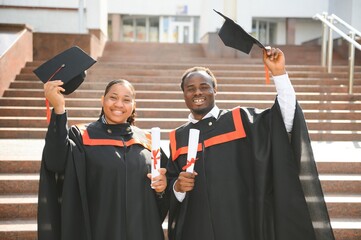Happy african american couple students in graduation dresses