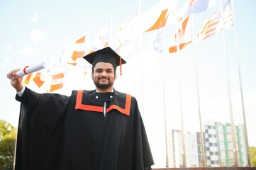 Handsome indian graduate in graduation glow with diploma