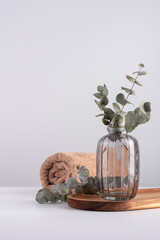 Beautiful eucalyptus branches in glass vase and terry towel