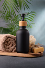 A black dispenser bottle of lotion or shower gel for body care product mock-up in tropical spa interior