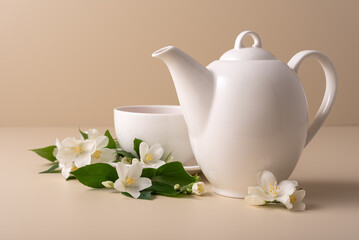 A white tea cup and teapot with a jasmine flowers