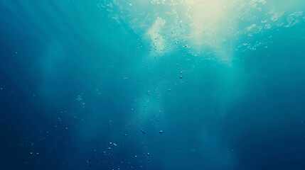 Underwater light rays and bubbles. Sunlight shining through the surface of a deep blue ocean with air bubbles rising to the top.