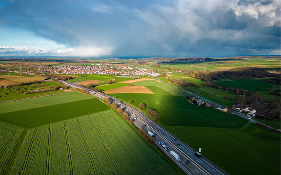 high angle view of the highway between the fields with the rain clouds casting a shadow