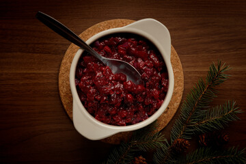 Top view of a wooden table with a bowl of cranberry sauce