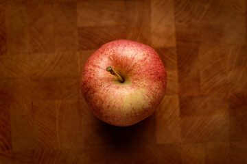 Top view of a red apple placed on a wooden table surface