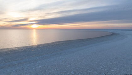 Fototapeta premium Sunset colored panoramic view of the calm seabay with the edge of the cracked sea ice and open water