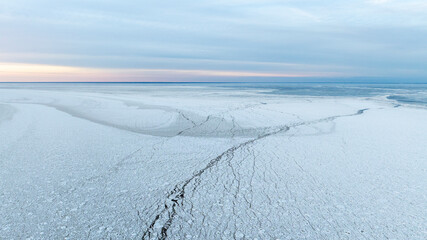 Sunset colored panoramic view of the calm seabay with the edge of the cracked sea ice and open water © Wirestock