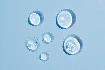 Liquid cream gel cosmetic smudge drops texture on blue background. cosmetic smears cream texture