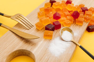 Candied fruit jelly on a wooden plate with spoon, fork and knife