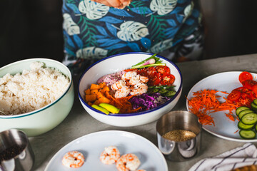 Poke bowl with shrimp prepared by the chef containing white rice, mango, avocado, tomato, etc.