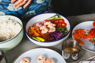 Poke bowl with shrimp prepared by the chef containing white rice, mango, avocado, tomato, etc.