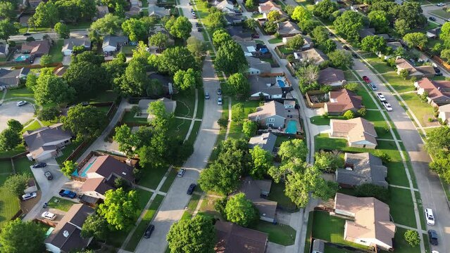 Flyover parallel residential streets with back alleys and row of single-family houses surrounding by lush green trees in suburbs Dallas Fort Worth metro complex, suburban homes swimming pool