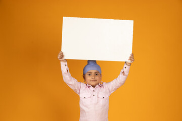 Happy Indian sikh boy child holding place card isolated on yellow background. Education,...
