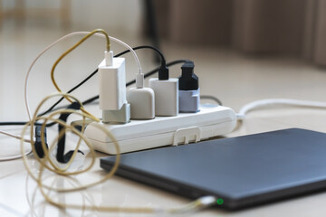 Electrical outlet with many chargers connected to it for a smartphone, laptop, microphone