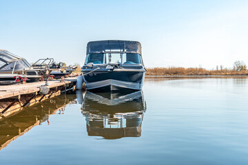 Fishing boats moored at wooden pontoon pier in early morning. Modern motorboats in small docks on...