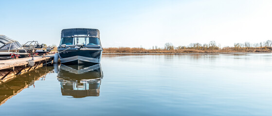 Fishing boats moored at wooden pontoon pier in early morning. Modern motorboats in small docks on...