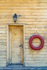 Red lifebuoy rings hang on wooden wainscoting wall of building by river. Lifeguards station with...