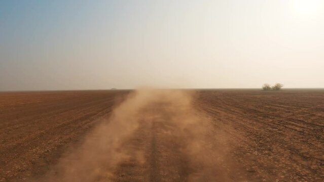 4K view of desert sand flying after off-road vehicle passing through desert in kutch, Gujarat, india. Desert safari adventure sports. Dust rising in the air due to car driving on dirt road.